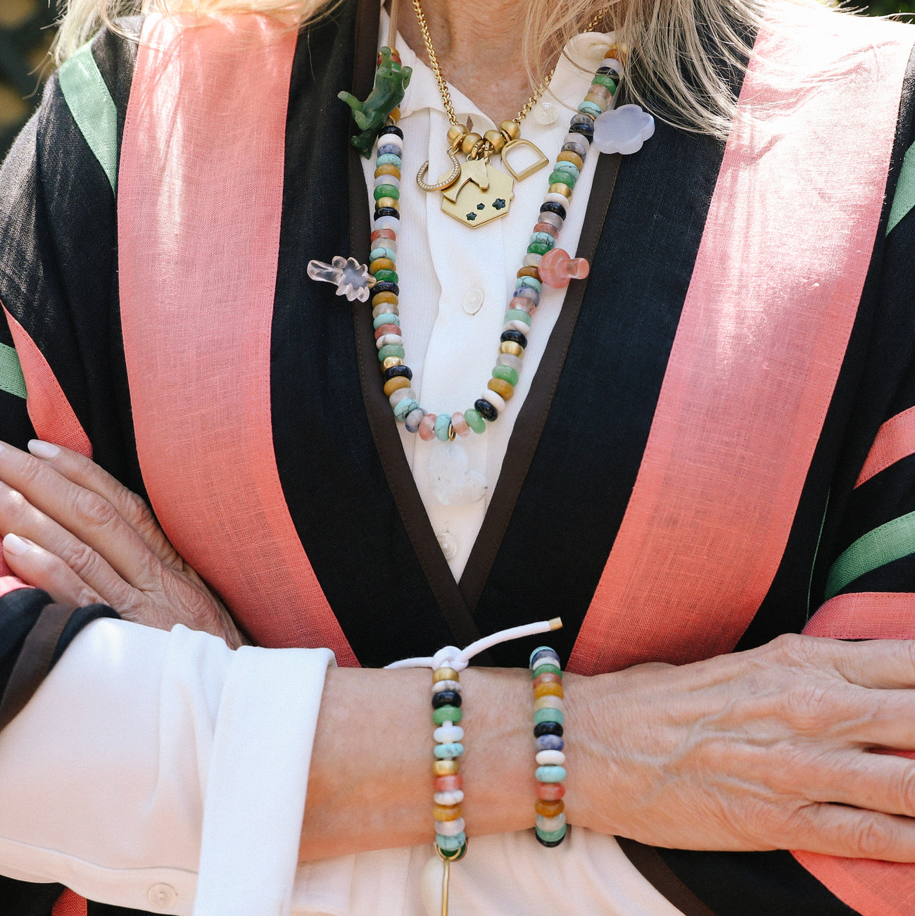 styled necklace and bracelet looks on person wearing pink and black jacket