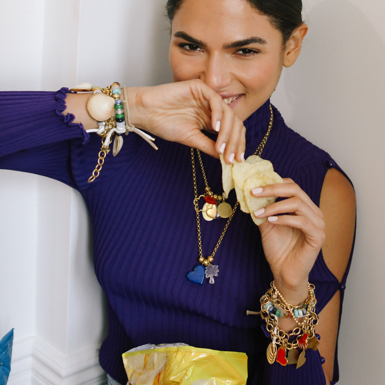 woman laughing holding potato chips with assorted bracelets on her wrists